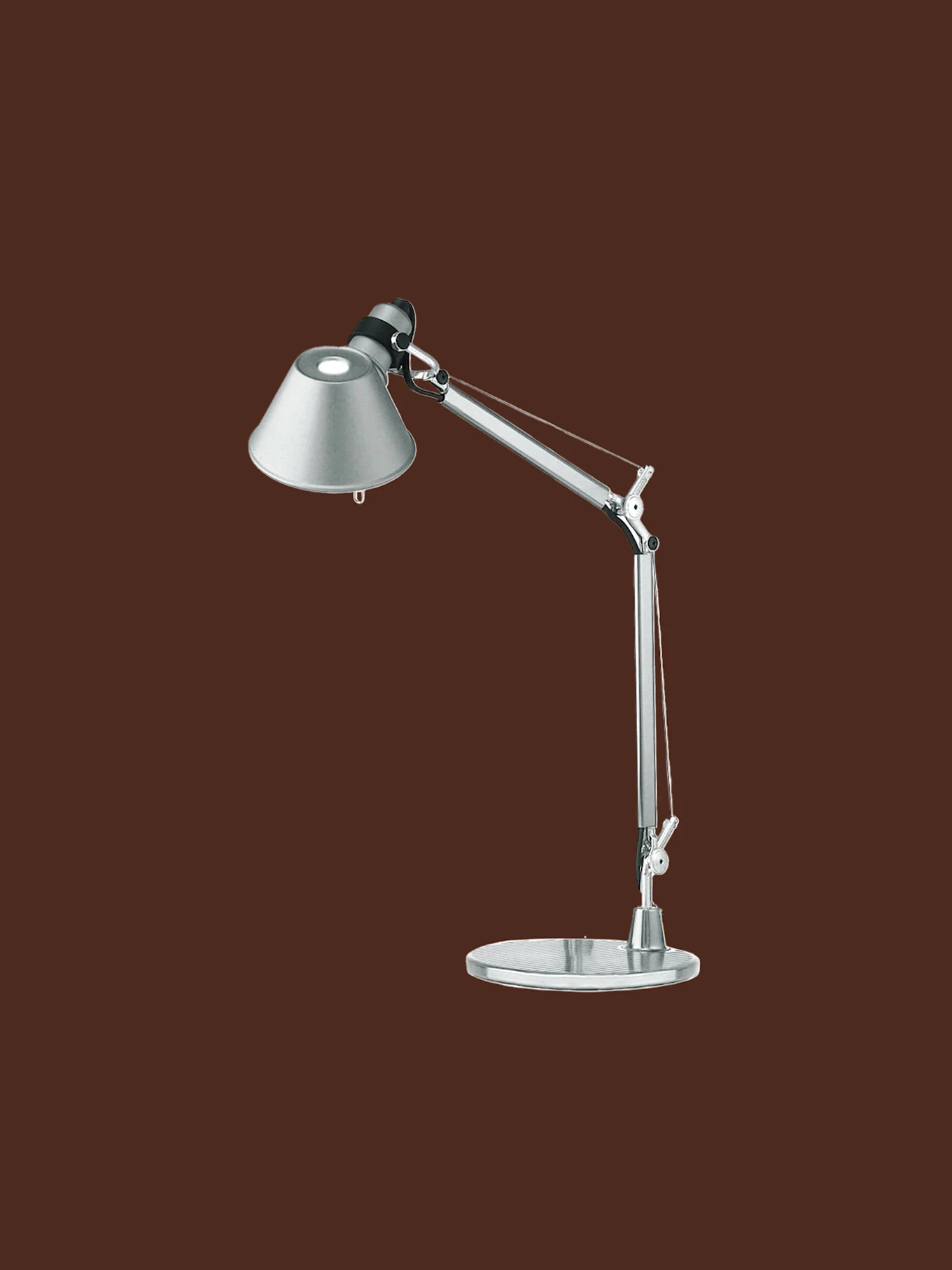Silverfärgad justerbar skrivbordslampa med konisk skärm och rund fot, tänd.