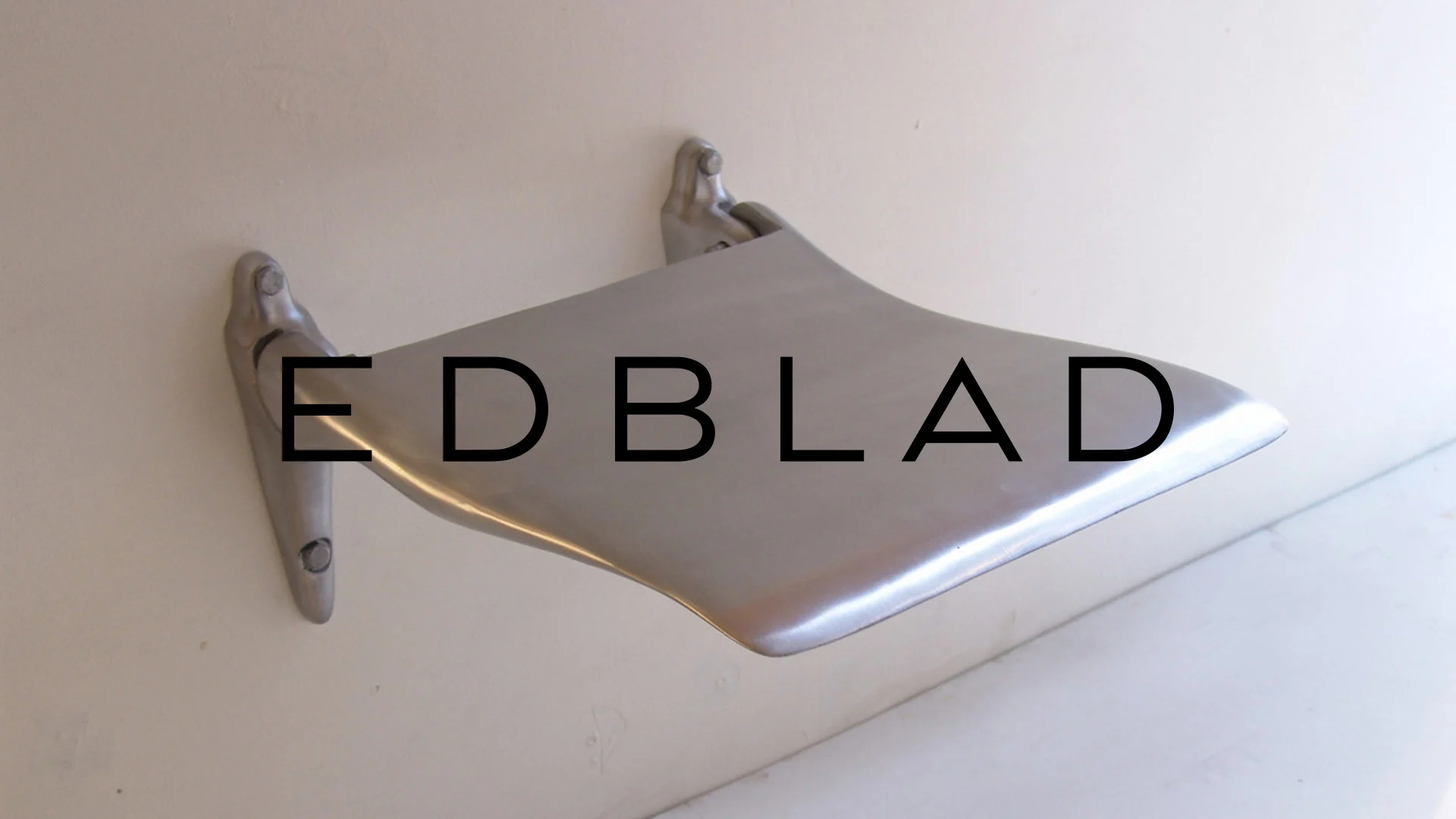 En elegant, böjd metallhylla eller -konsol monterad på en vit vägg.