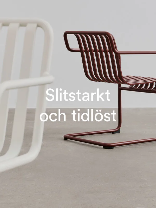 Två stolar, en vit och en rödbrun med ribbad rygg, minimalistisk och tidlös design.