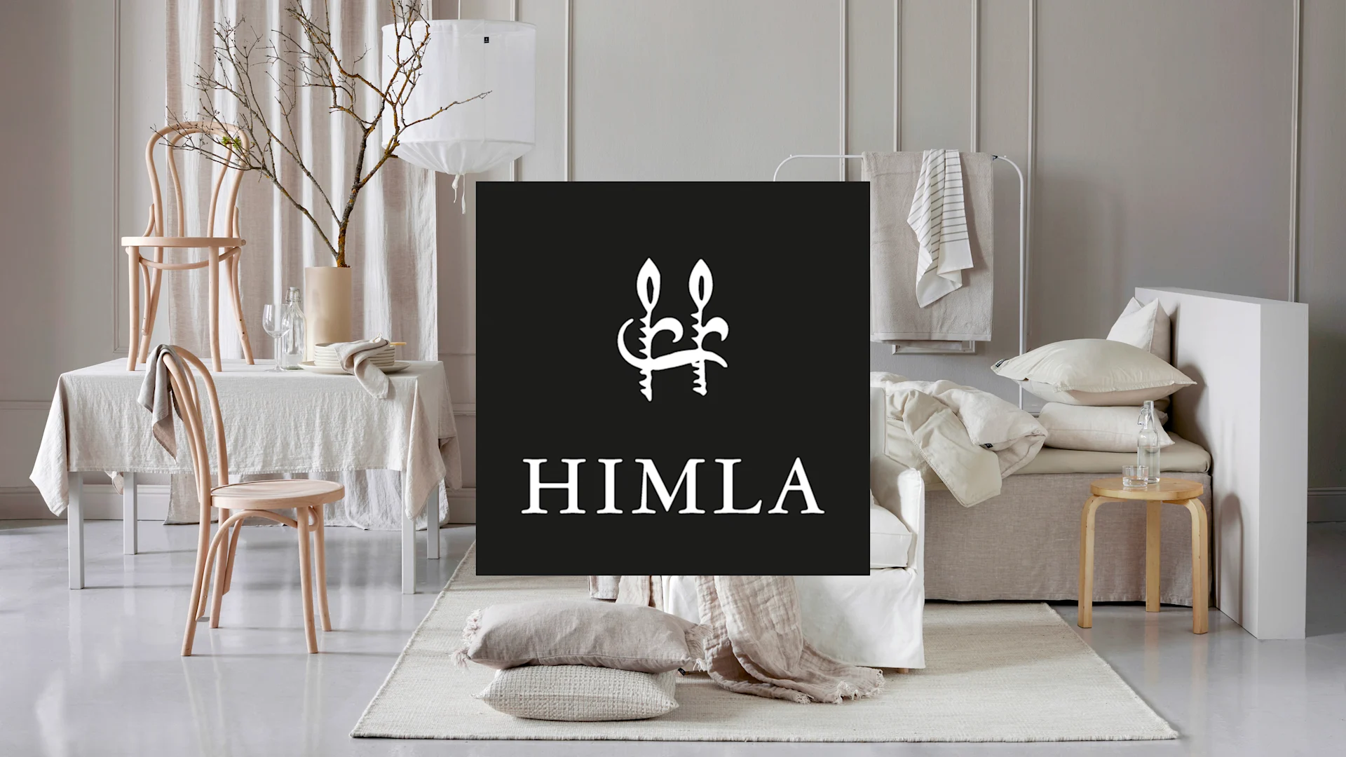 Himla-logotyp i ett neutralt rum med linnetextilier, trästolar och minimalistisk inredning.