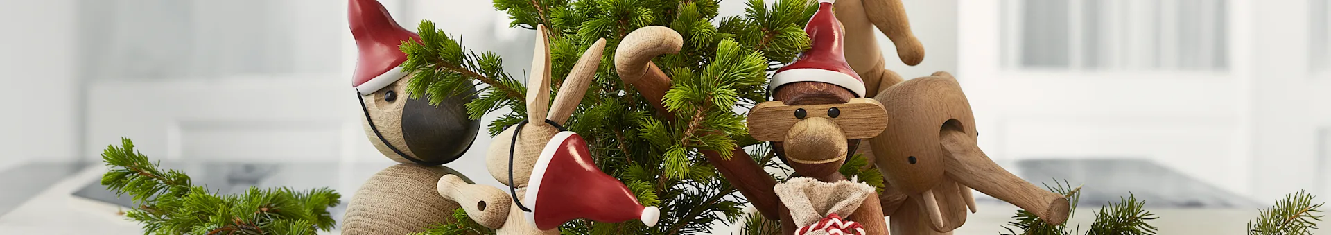 Juldekoration med träfigurer av fågel, kanin, apa och elefant, alla med tomteluvor och granris.