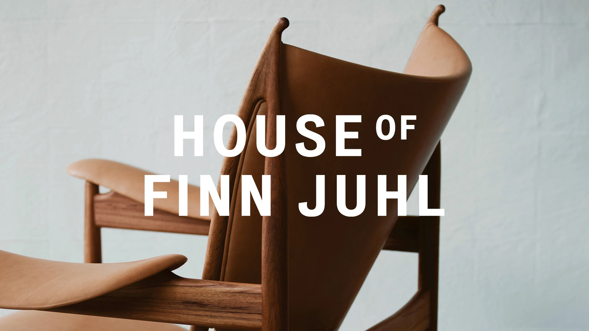 Midcentury träfåtölj med ljust brunt läder, och texten HOUSE OF FINN JUHL.