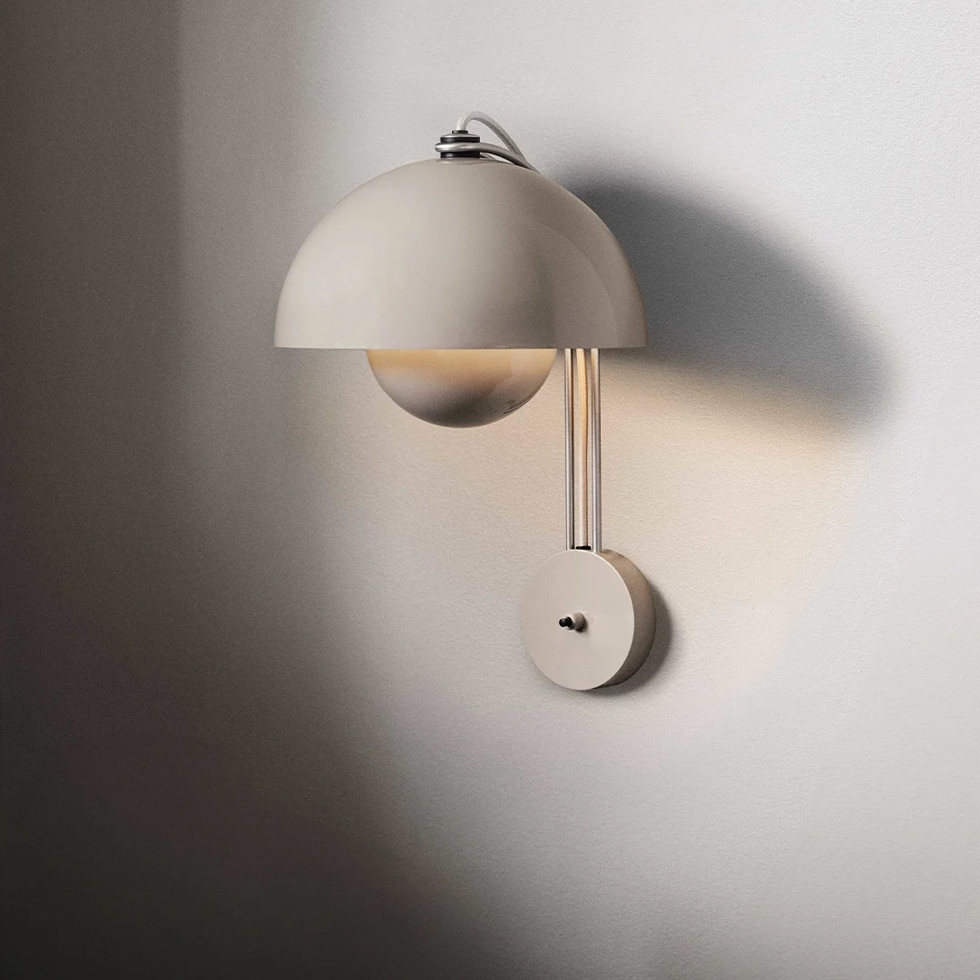 En ljus, modern vägglampa med kupolformad skärm och en rund glödlampa, monterad på en vägg.