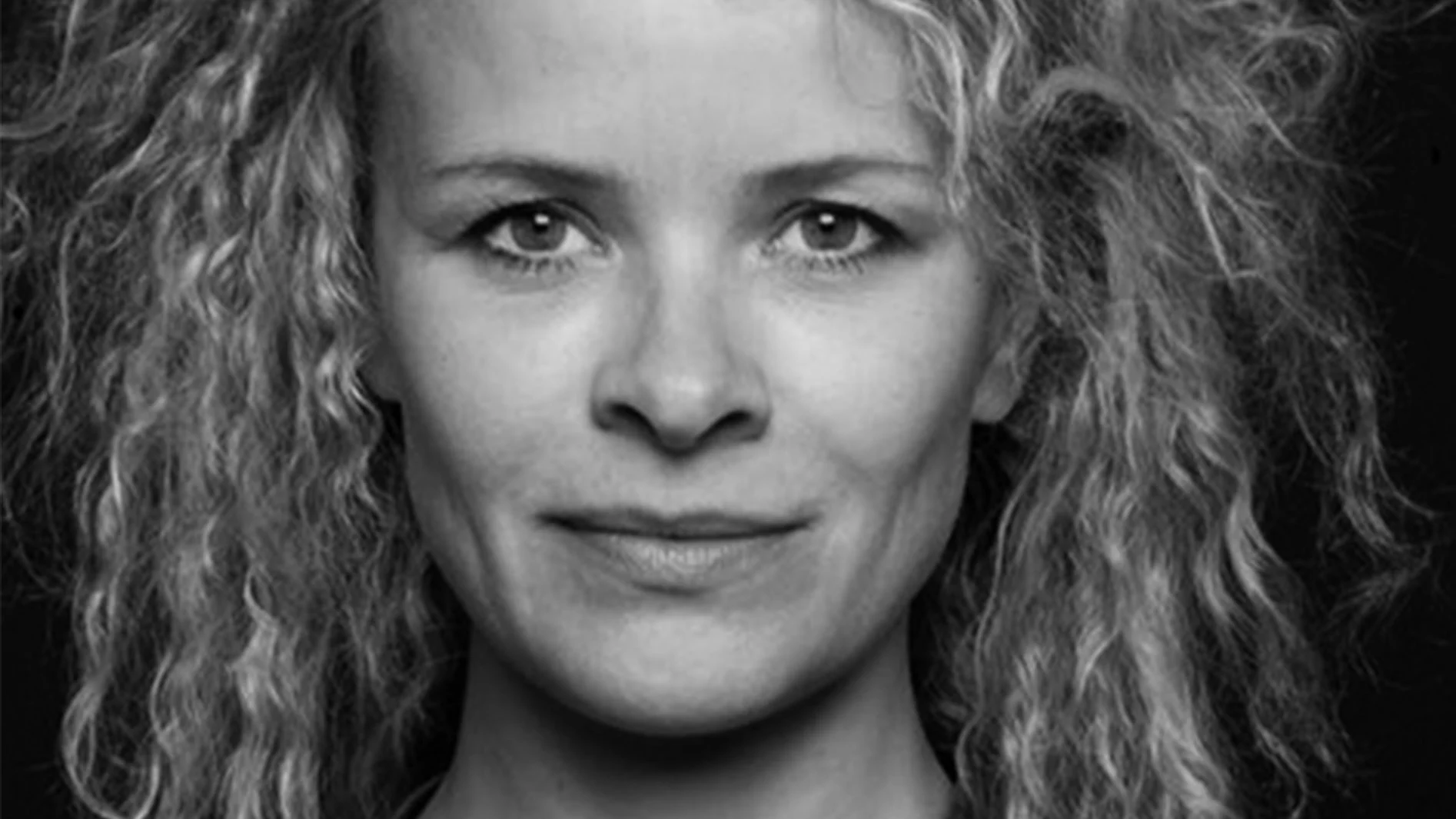 Närbild, svartvitt porträtt av en kvinna med lockigt hår som tittar framåt.