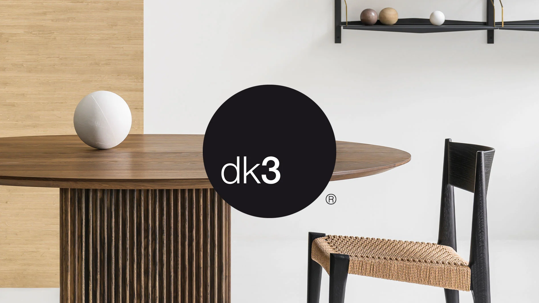 Runt matbord i trä med vit kula, svart stol med flätad sits, och dk3-logotyp.